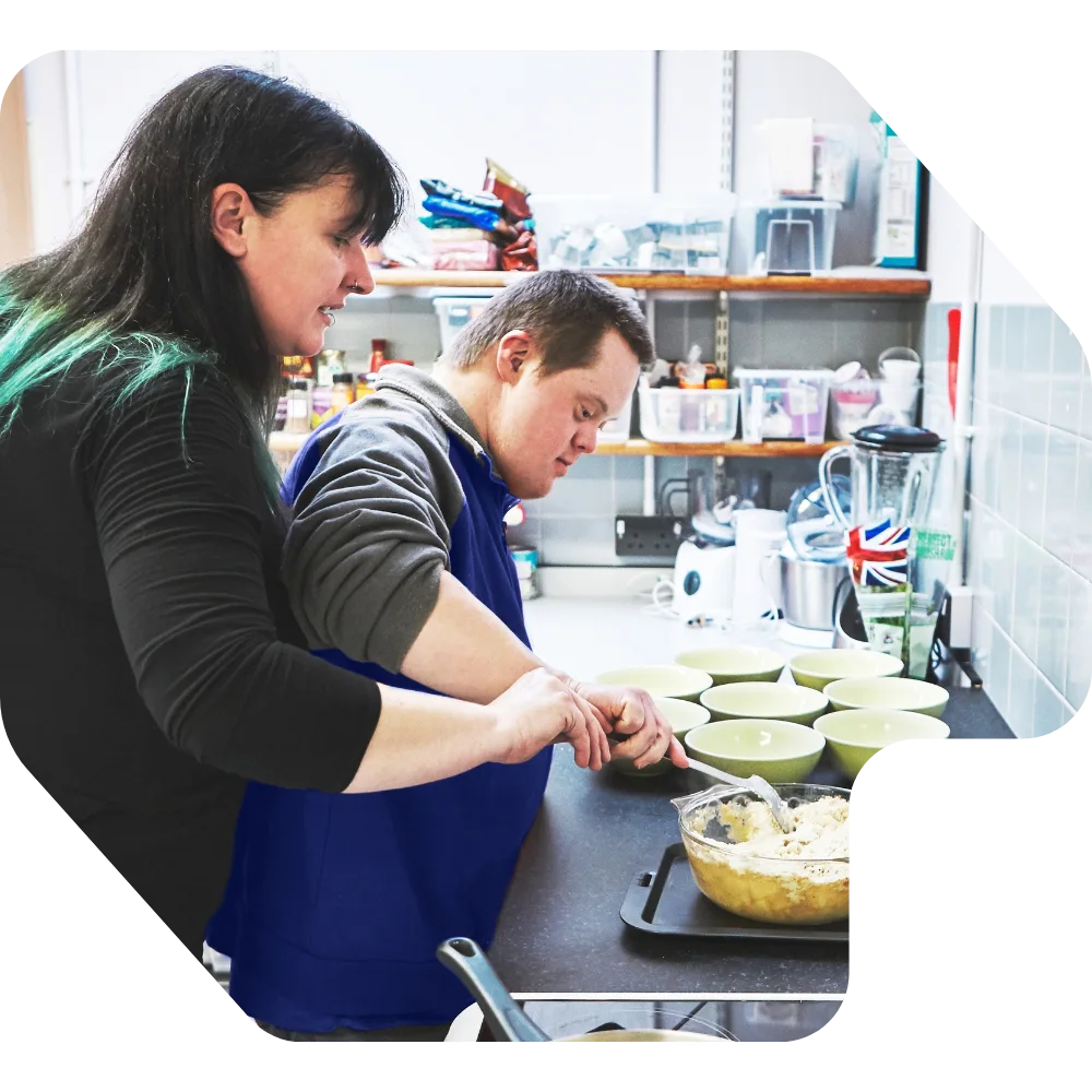 Disabled man cooking with support worker