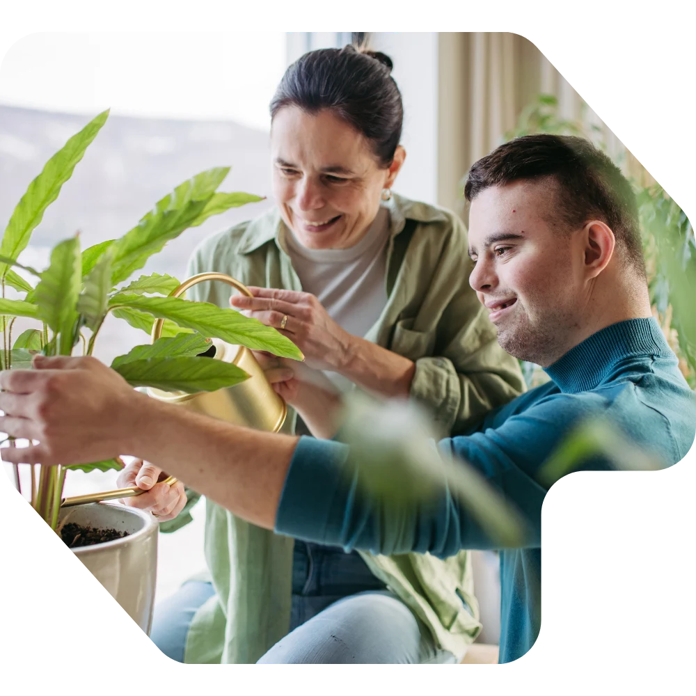 Disabled man and support worker watering plants