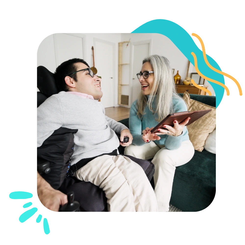 Disabled man in wheelchair laughing with support worker